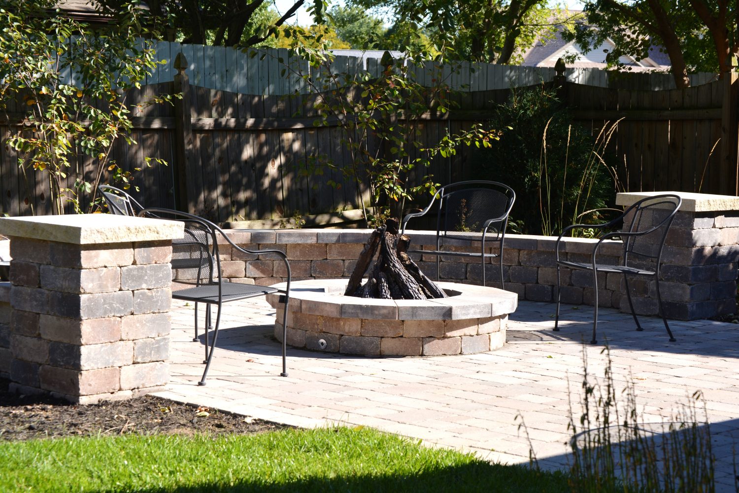 Built-in backyard fire pit on a paver surround by Plant Studio Landscape