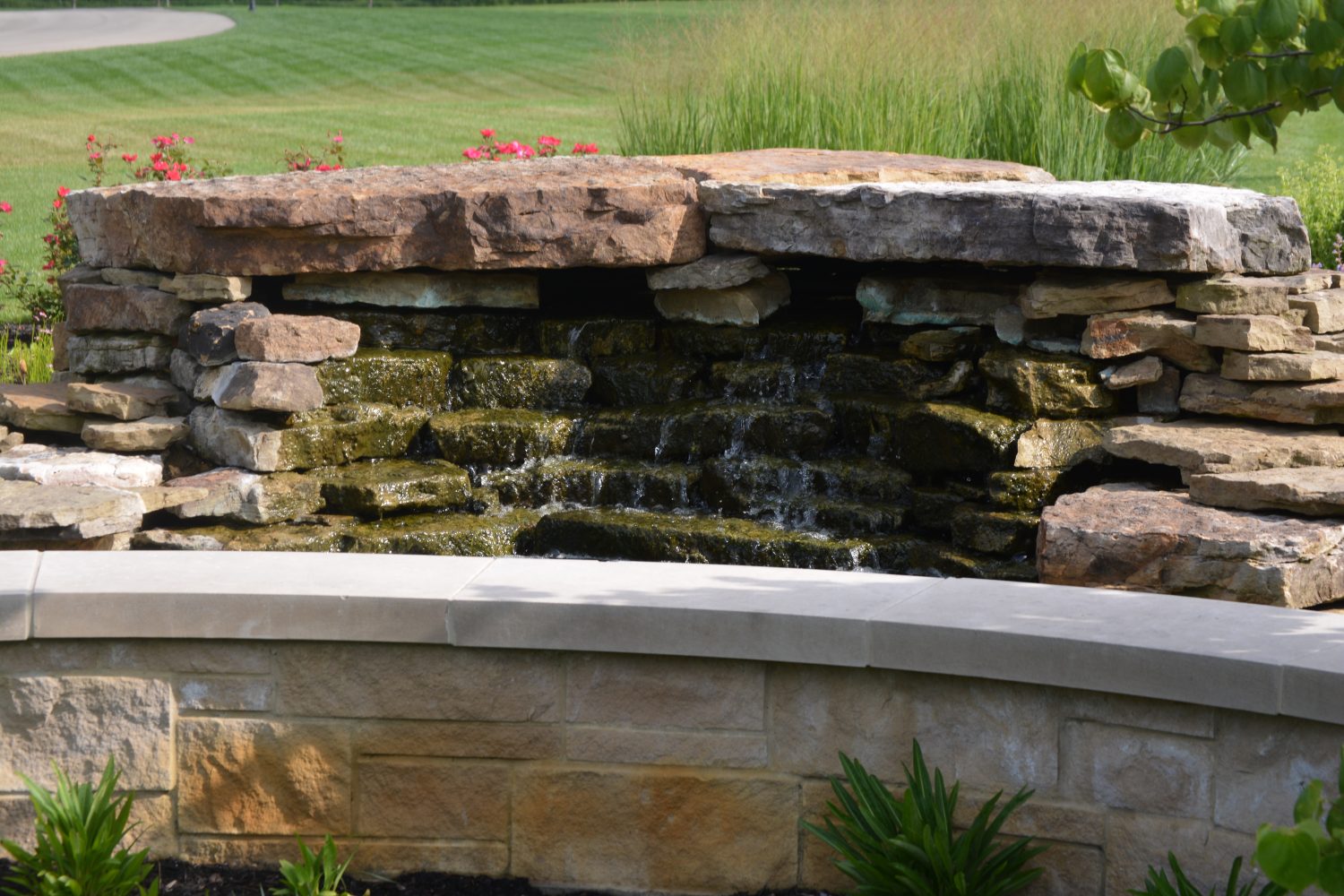 Stone retaining wall and integrated water feature by Plant Studio Landscape