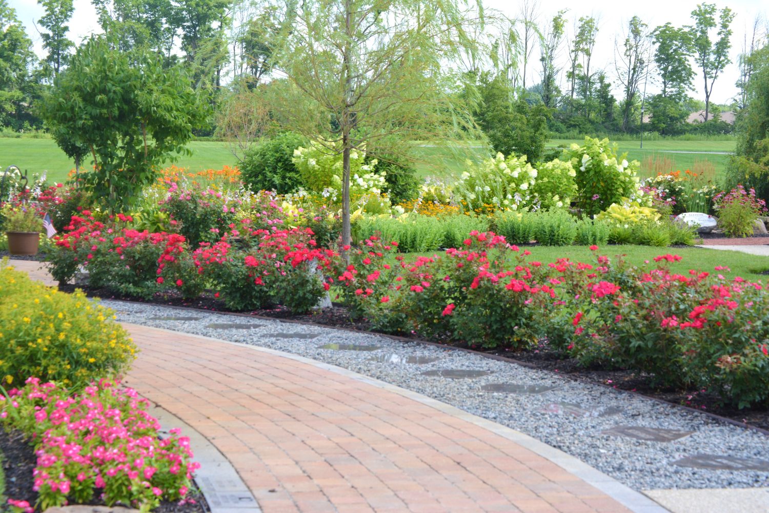 Naturalistic stone and gravel path lined with annuals by Plant Studio Landscape